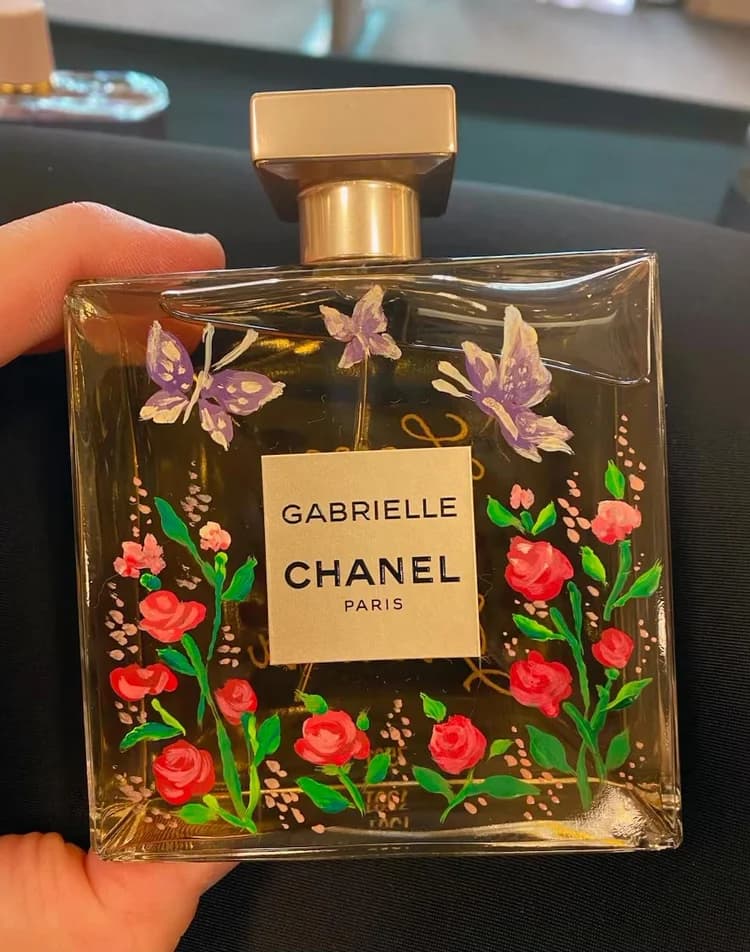 A glass fragrance bottle hand-painted with roses and butterflies during a live personalization session.