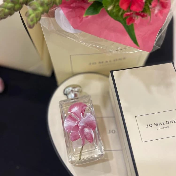 Close view of a perfume bottle painted with a single pink flower.