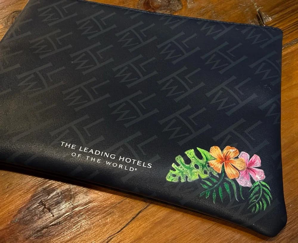 A navy leather pouch hand-painted with tropical flowers at a hotel event.