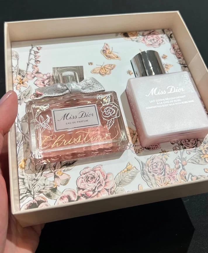 A fragrance gift set personalized with a hand-lettered name and floral linework.